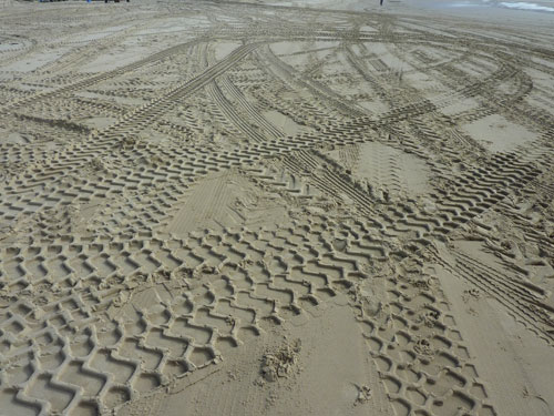 Reifenspuren im Sand.